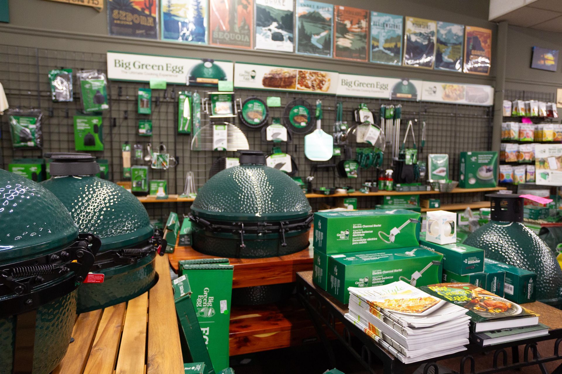 A retail display showcases Big Green Egg grills and accessories, predominantly in green, inside a store.
