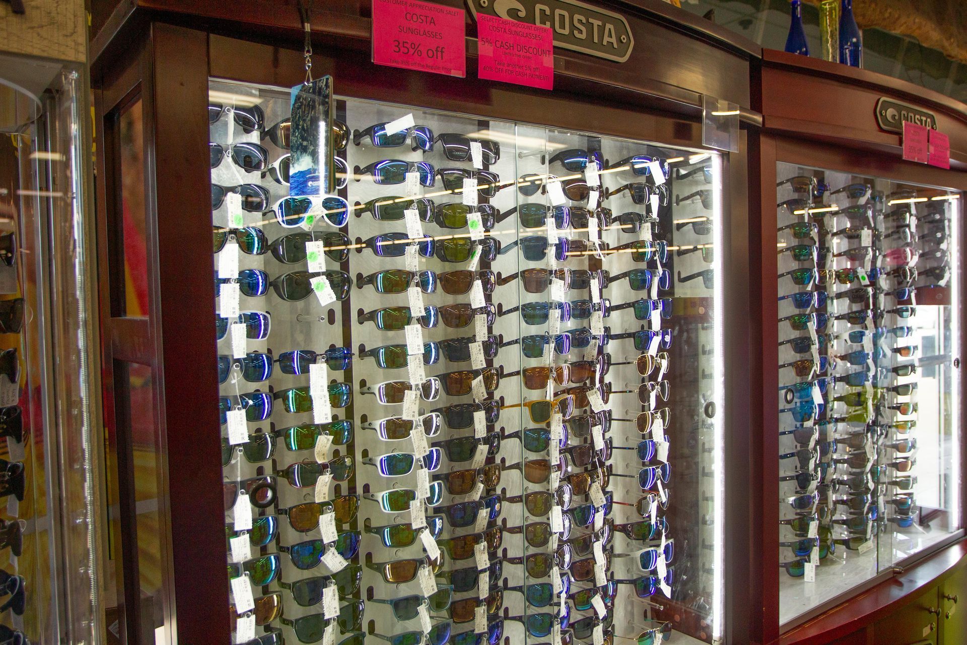 Sunglasses displayed in a well-lit cabinet at a store, with a variety of colors and styles.