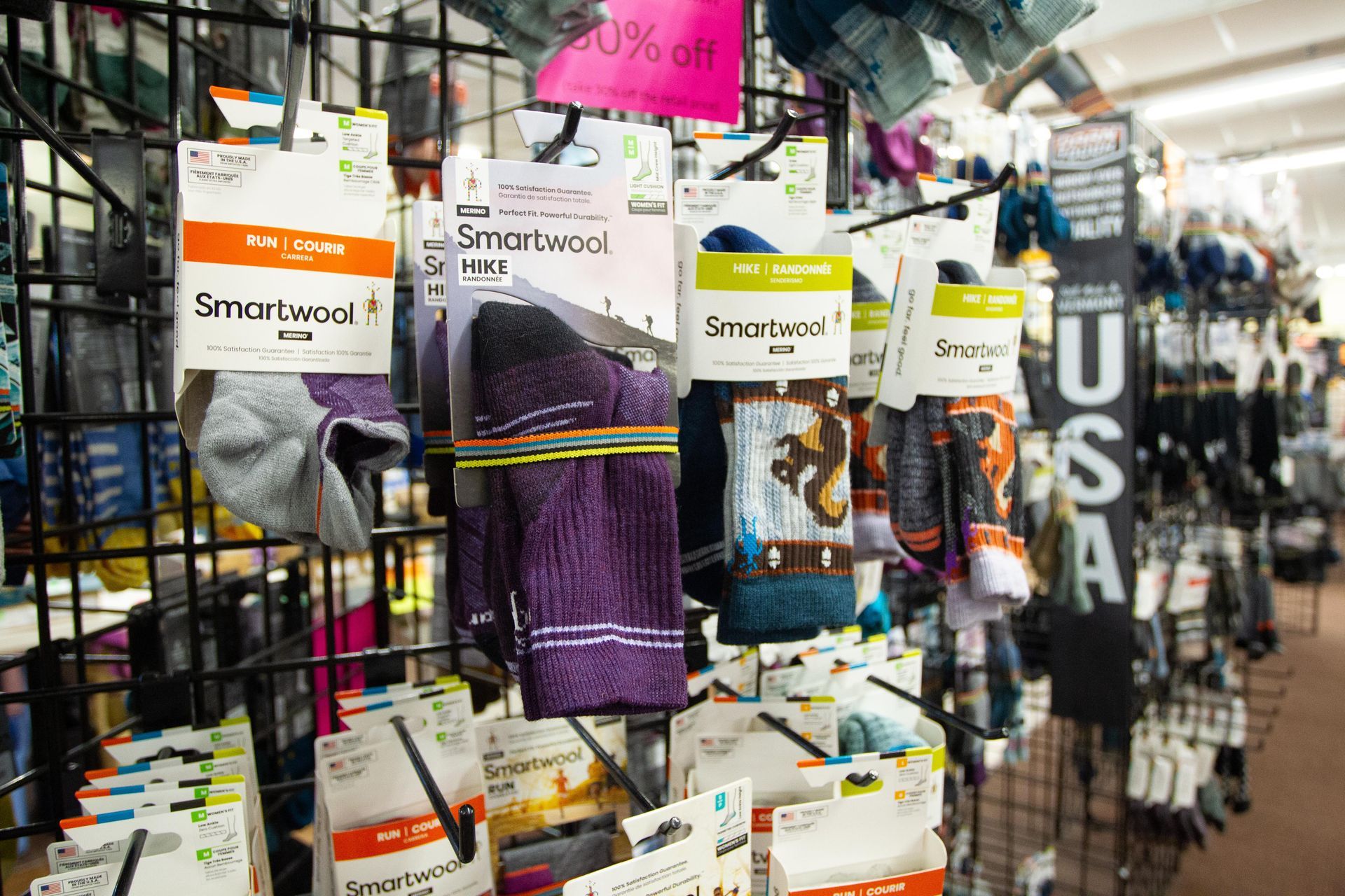 Display of Smartwool hiking socks for sale on a store rack. Various colors and designs of socks are packaged.