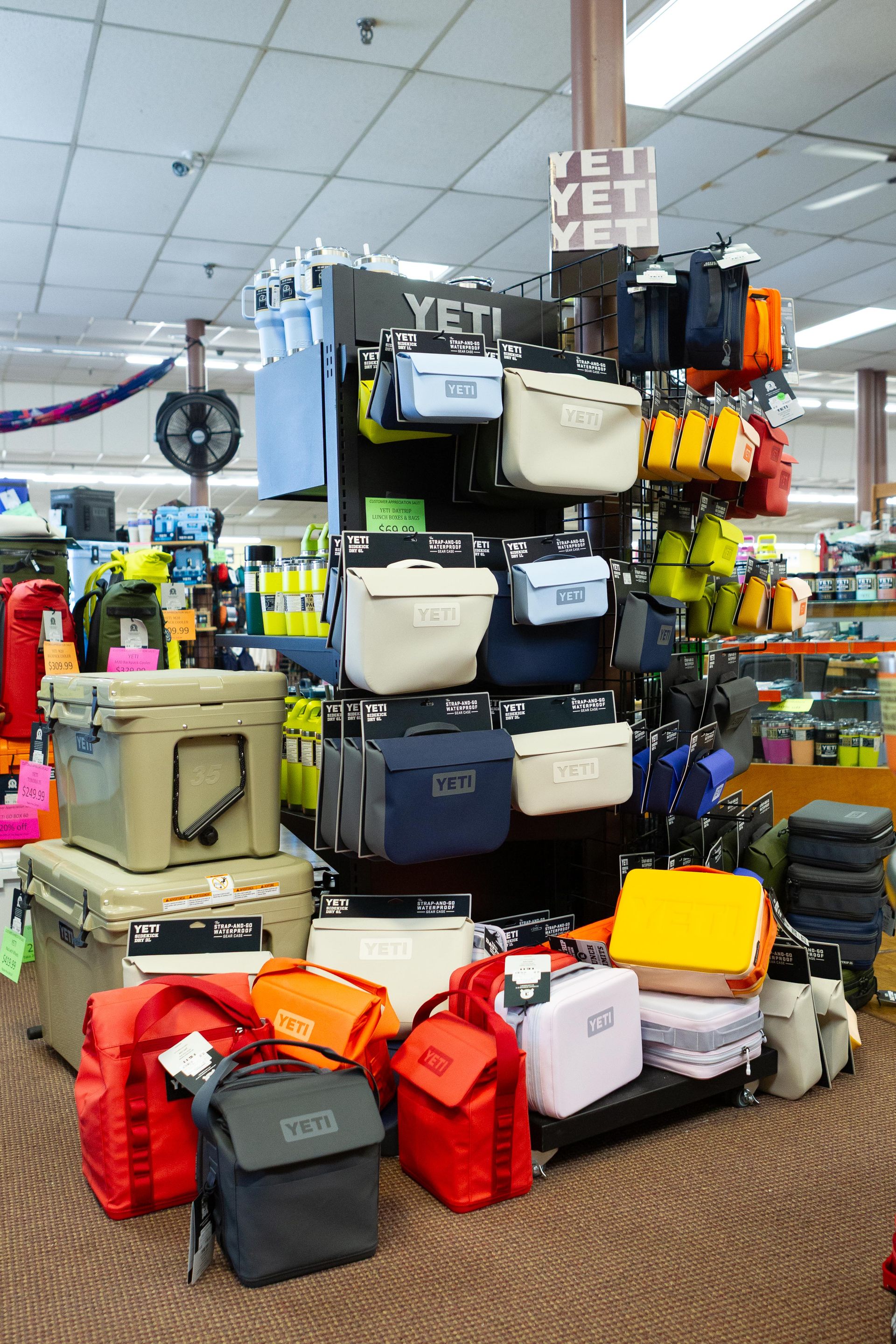 A retail display showcasing various Yeti coolers and bags, with a brown and black color scheme in a store setting.