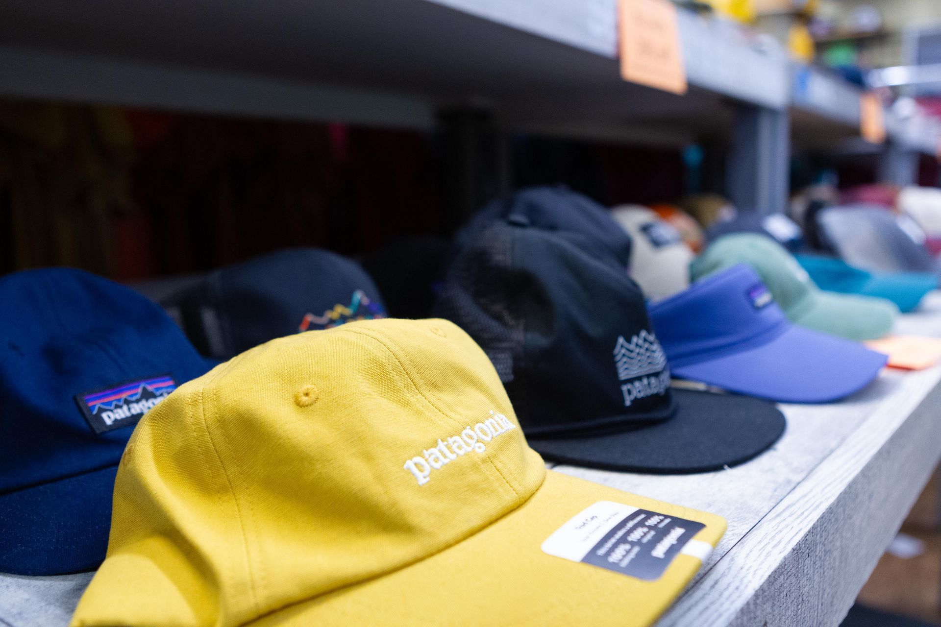 Close-up of a shelf displaying various Patagonia hats in different colors like yellow, blue, and black.