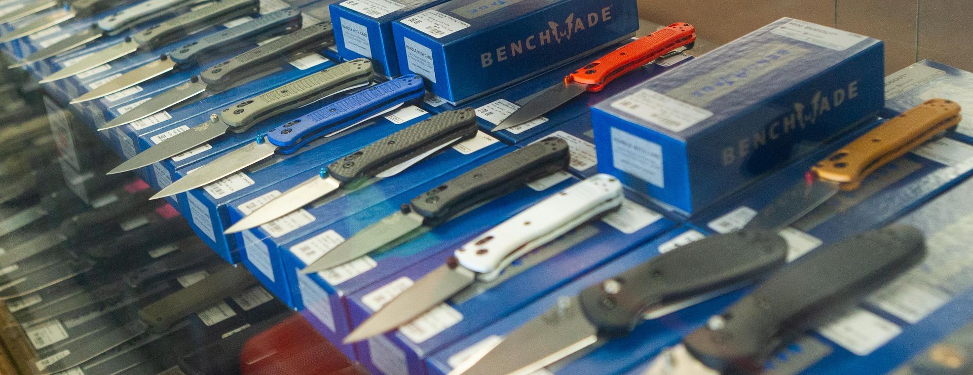 A display of folding knives, some open, on top of blue boxes in a store.