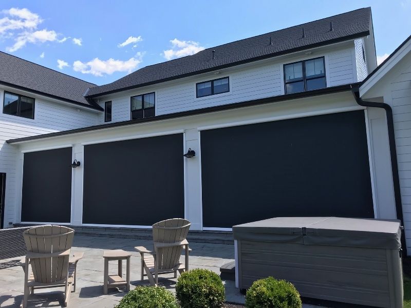 A large white house with a patio and chairs in front of it.