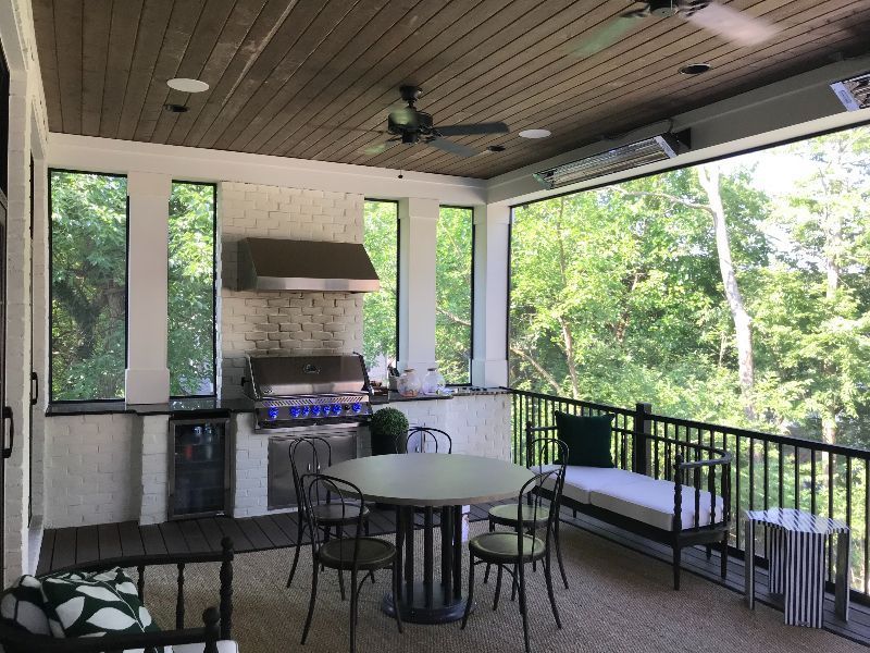 A screened in porch with a table and chairs and a grill.