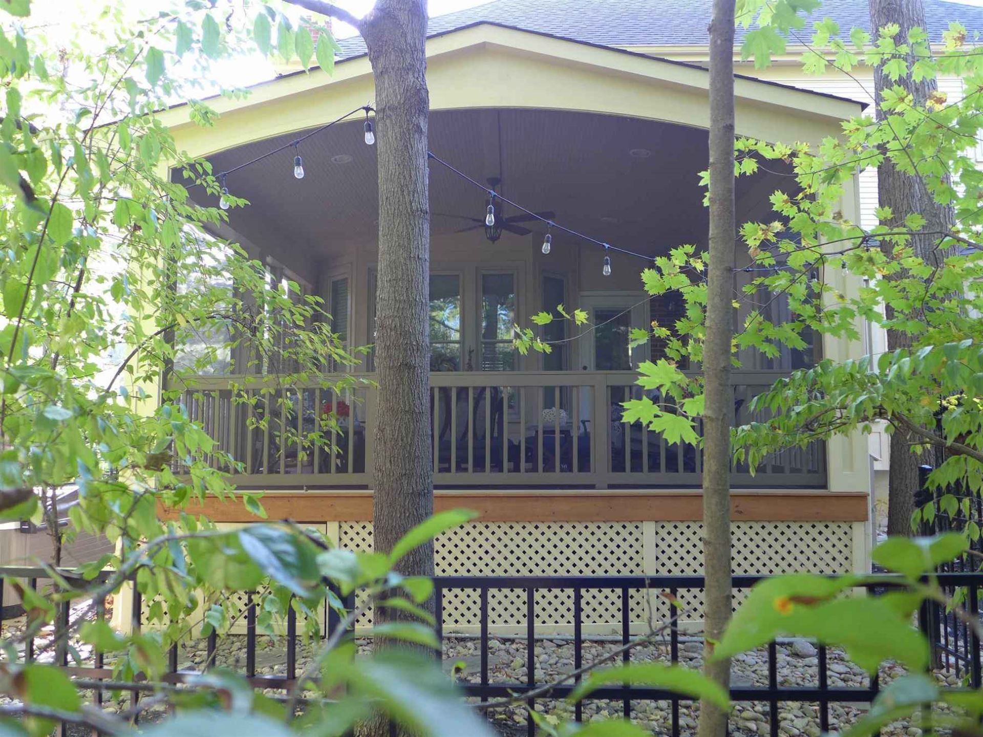 A house with a screened in porch is surrounded by trees.