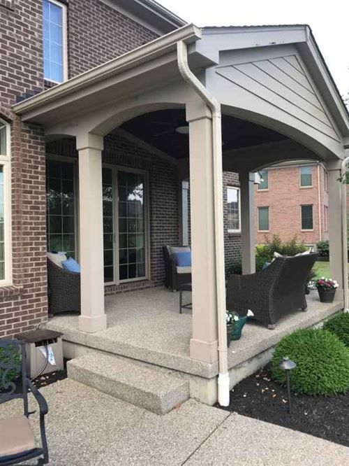 A brick house with a covered porch with furniture on it