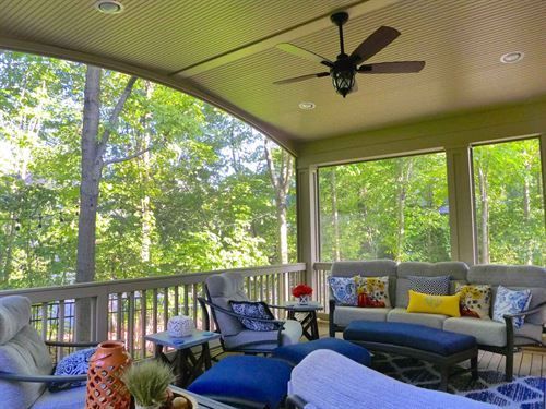 A screened in porch with furniture and a ceiling fan.