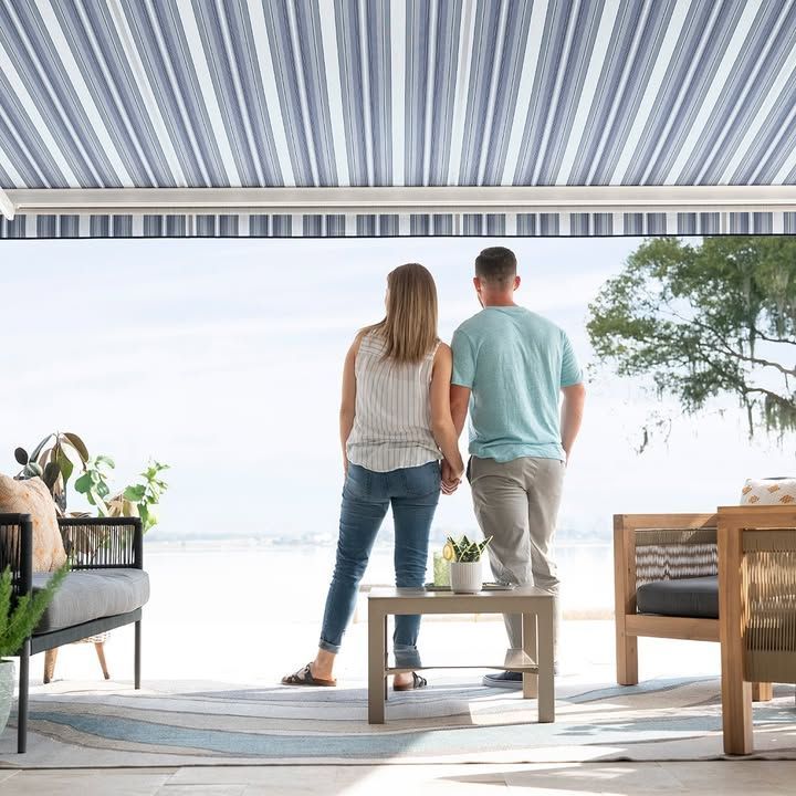 A man and a woman are standing under an awning on a patio.