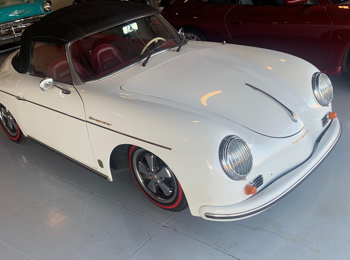 A white porsche speedster is parked in a garage.