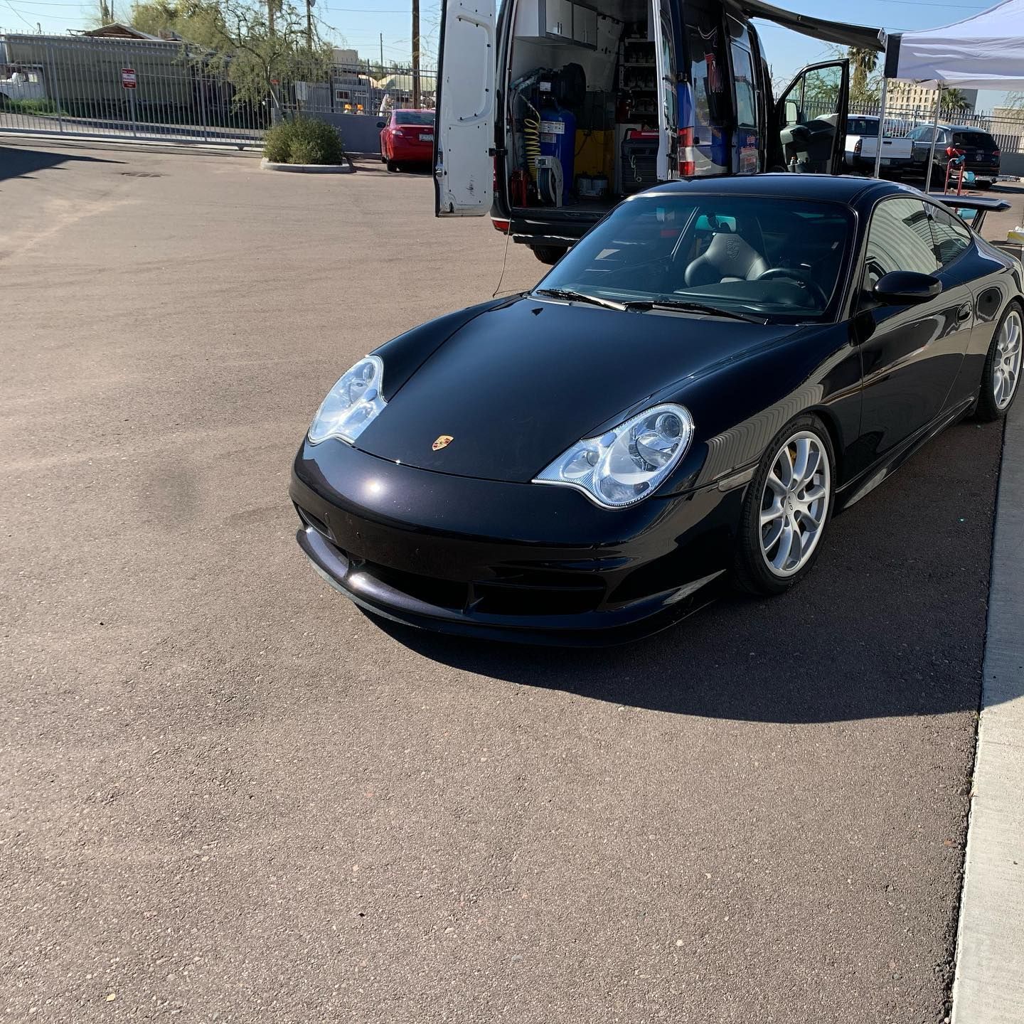 A black porsche is parked in a parking lot.