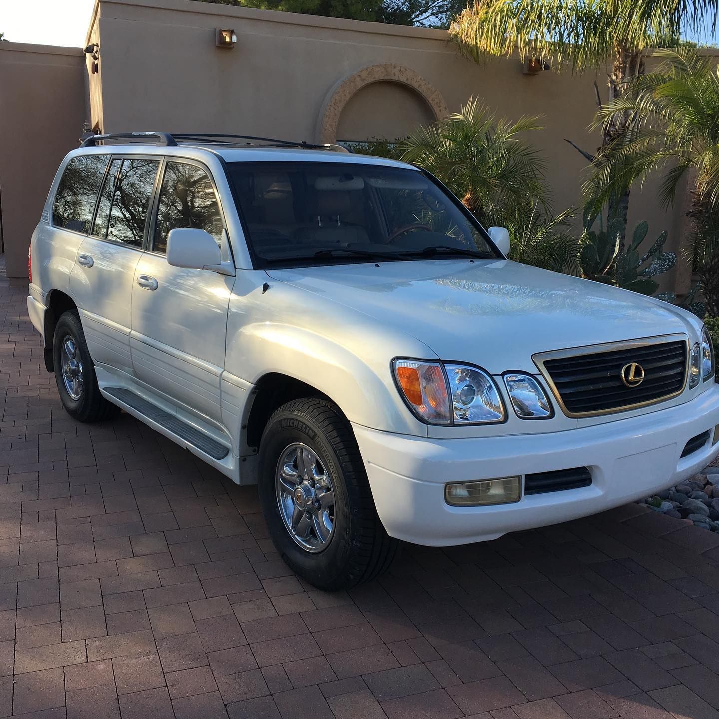 A white suv is parked on a brick driveway.