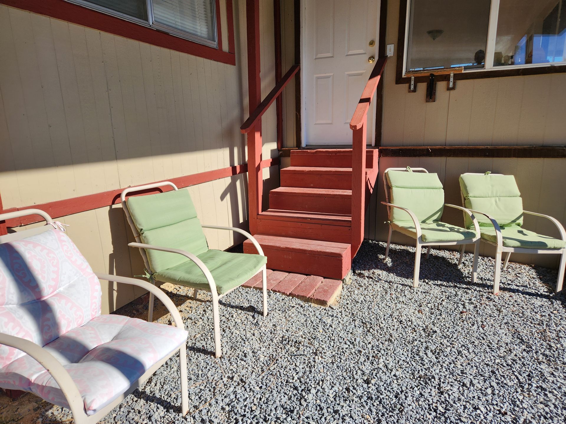 A patio with chairs and stairs in front of a house