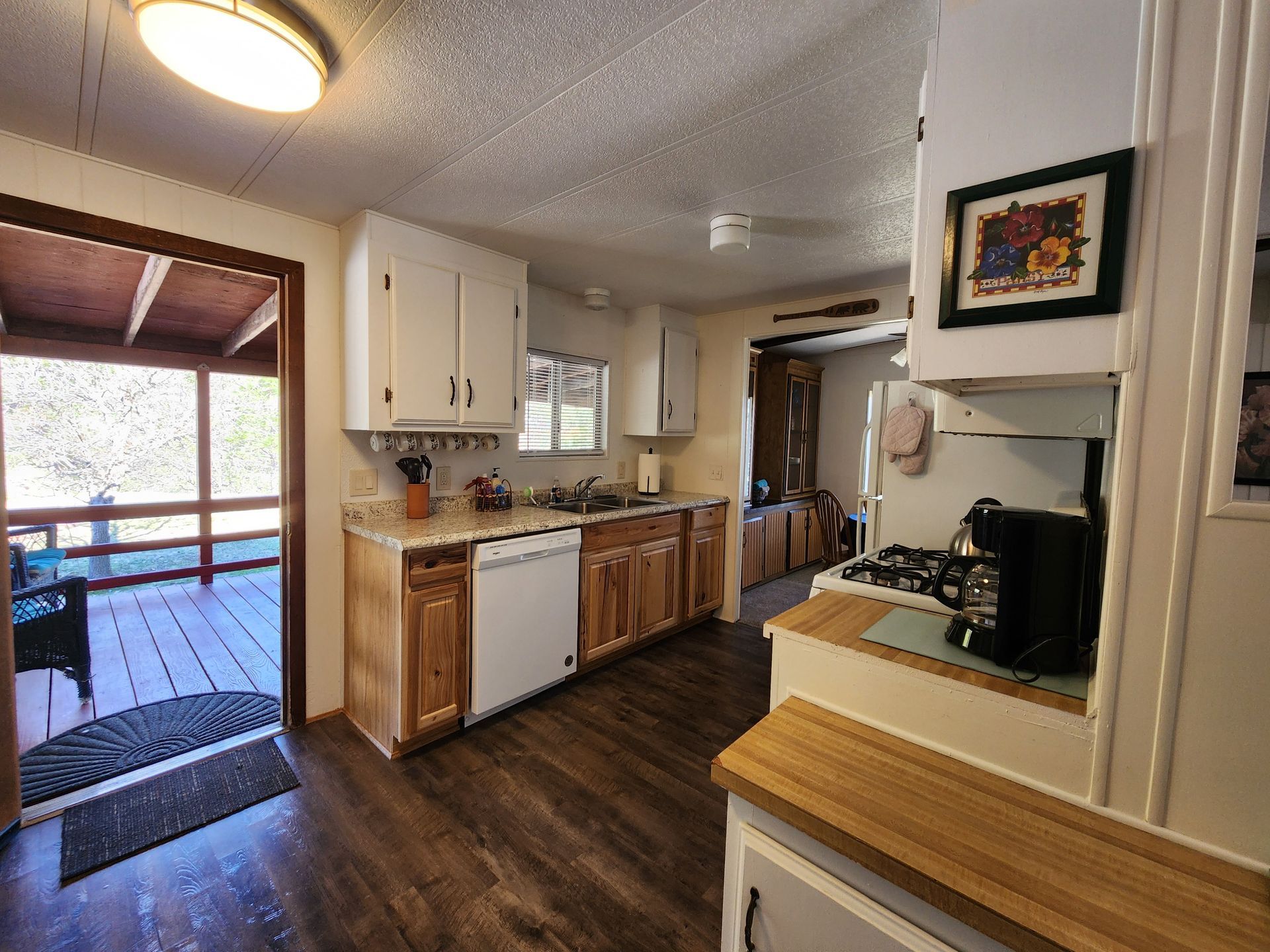 A kitchen with wooden floors, white cabinets, a stove, and a dishwasher.