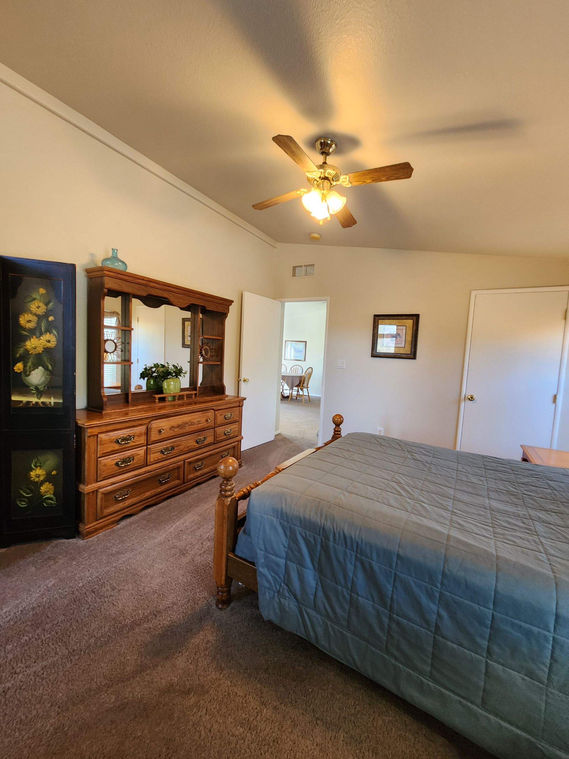 A bedroom with a bed , dresser , mirror and ceiling fan.