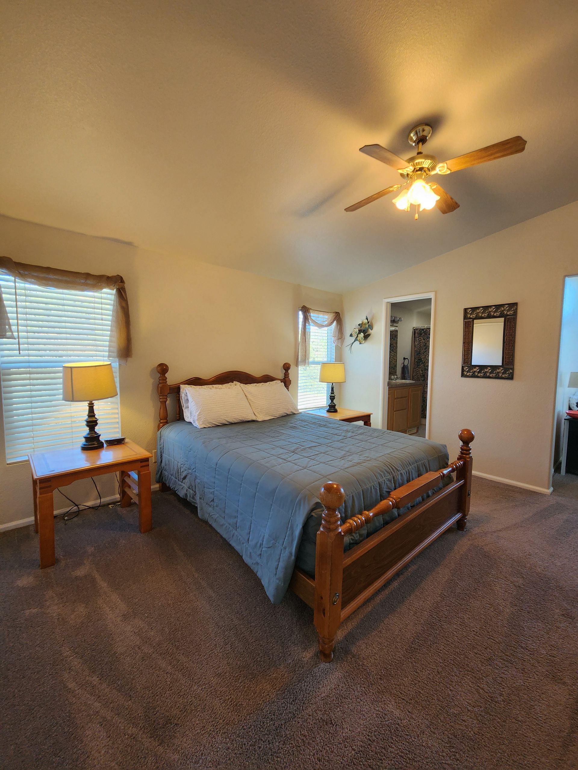 A bedroom with a bed , two lamps , a ceiling fan and a window.