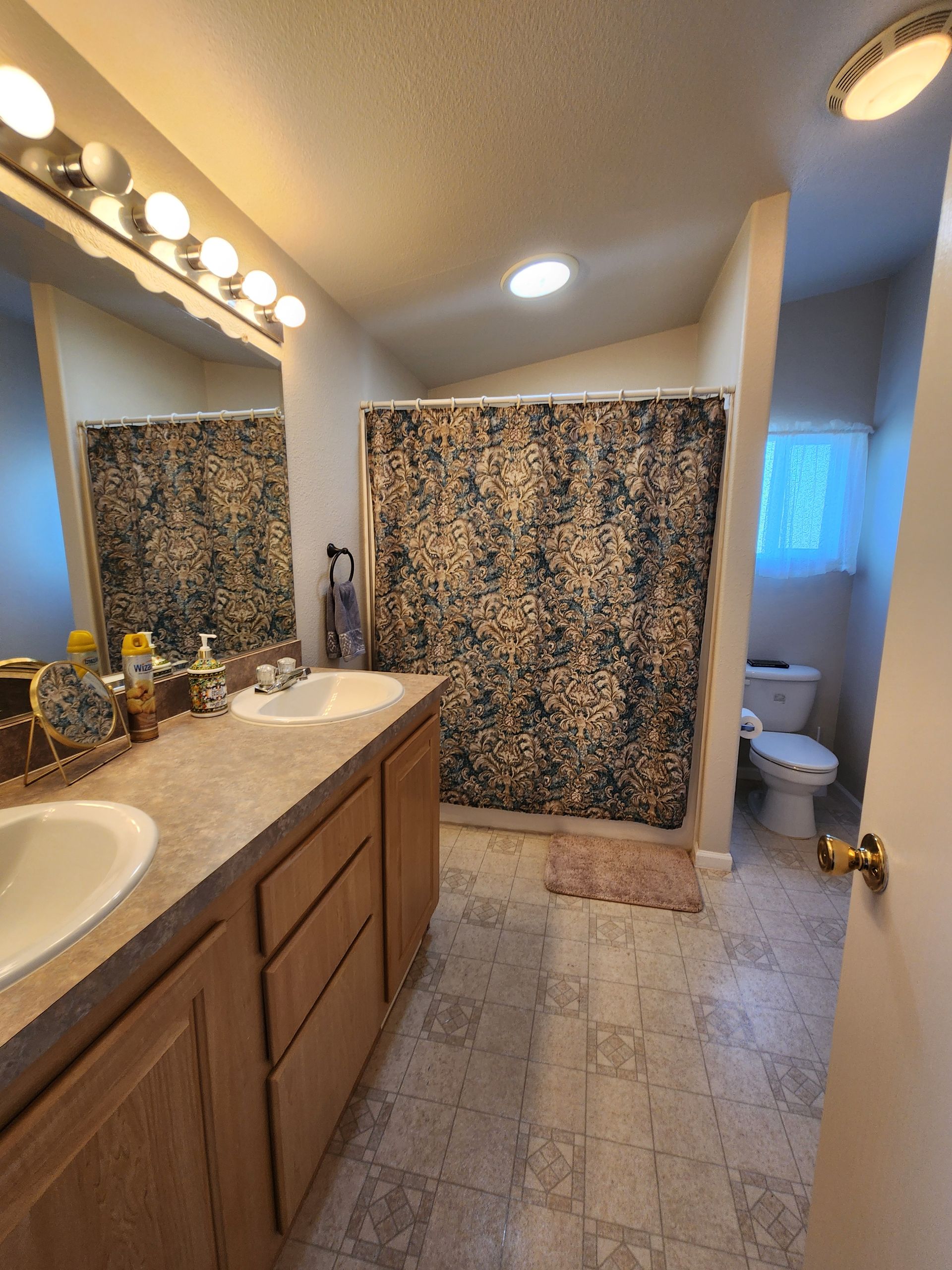 A bathroom with two sinks a toilet and a shower curtain