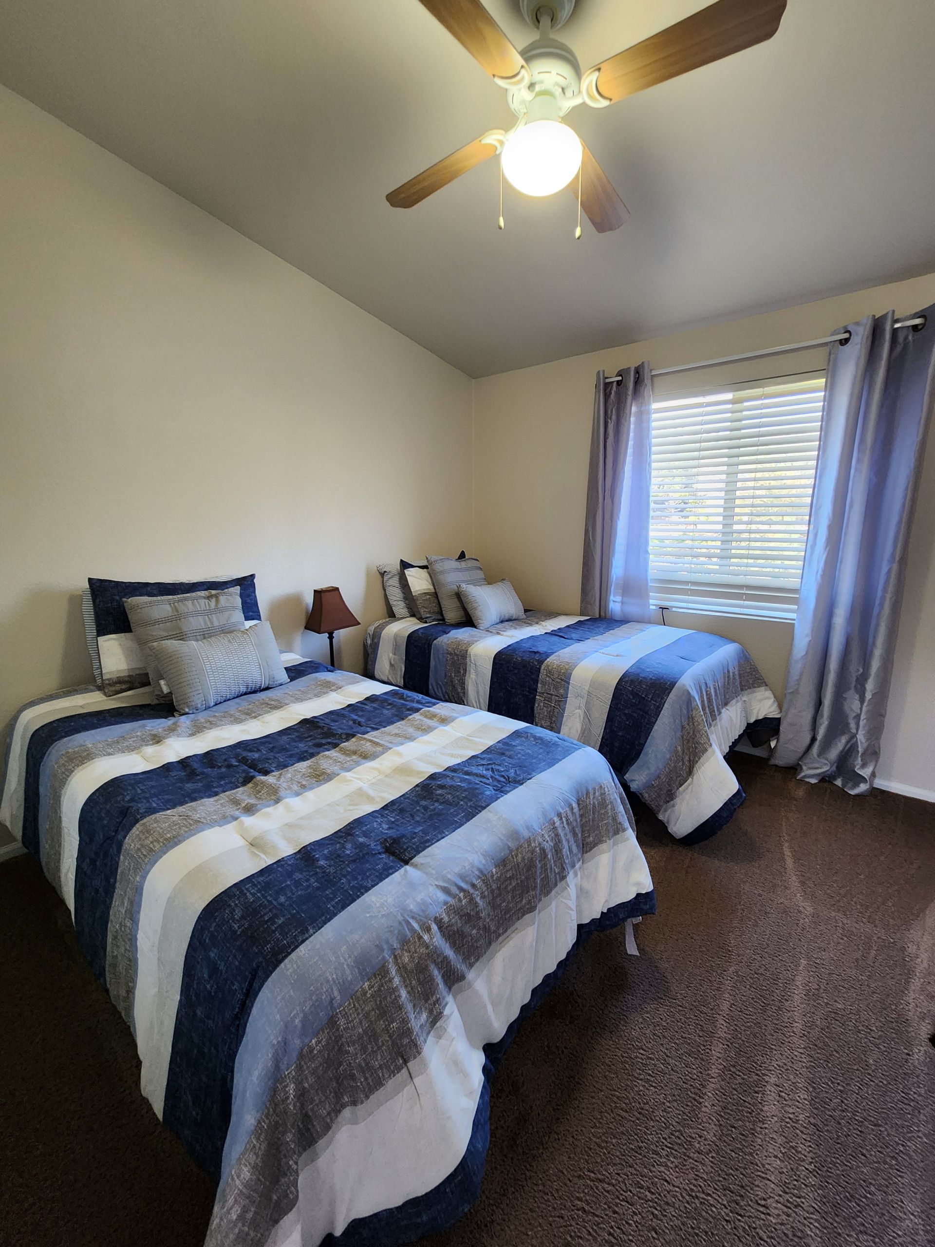A bedroom with two beds and a ceiling fan.