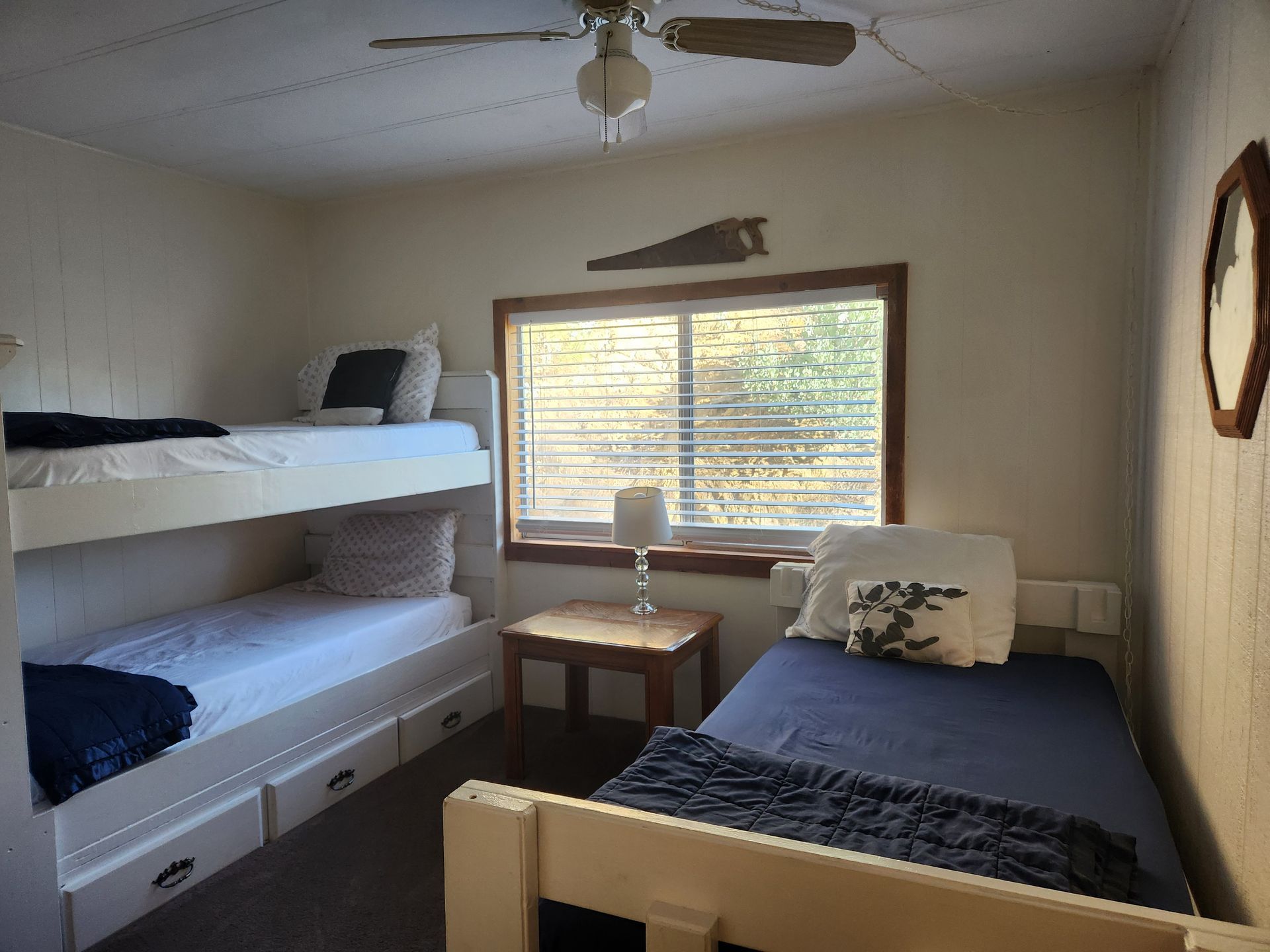 Bedroom with bunk bed and twin bed; window, nightstand, ceiling fan, and round mirror.