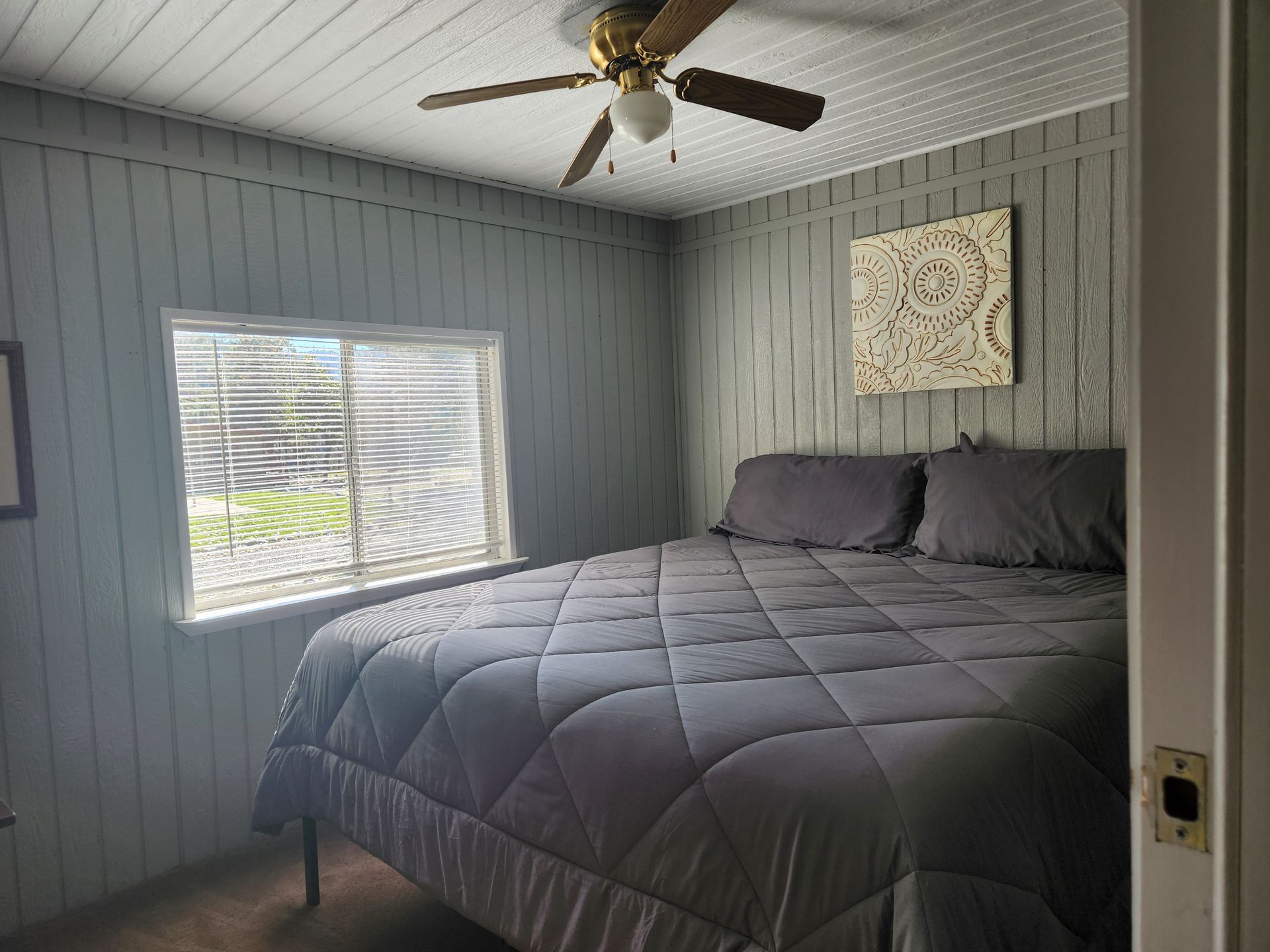 Bedroom with a gray bed, walls, and ceiling, a window, and a ceiling fan.