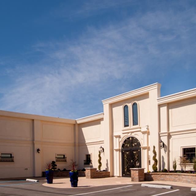 Exterior of a light beige building with a decorative entrance and a blue sky.