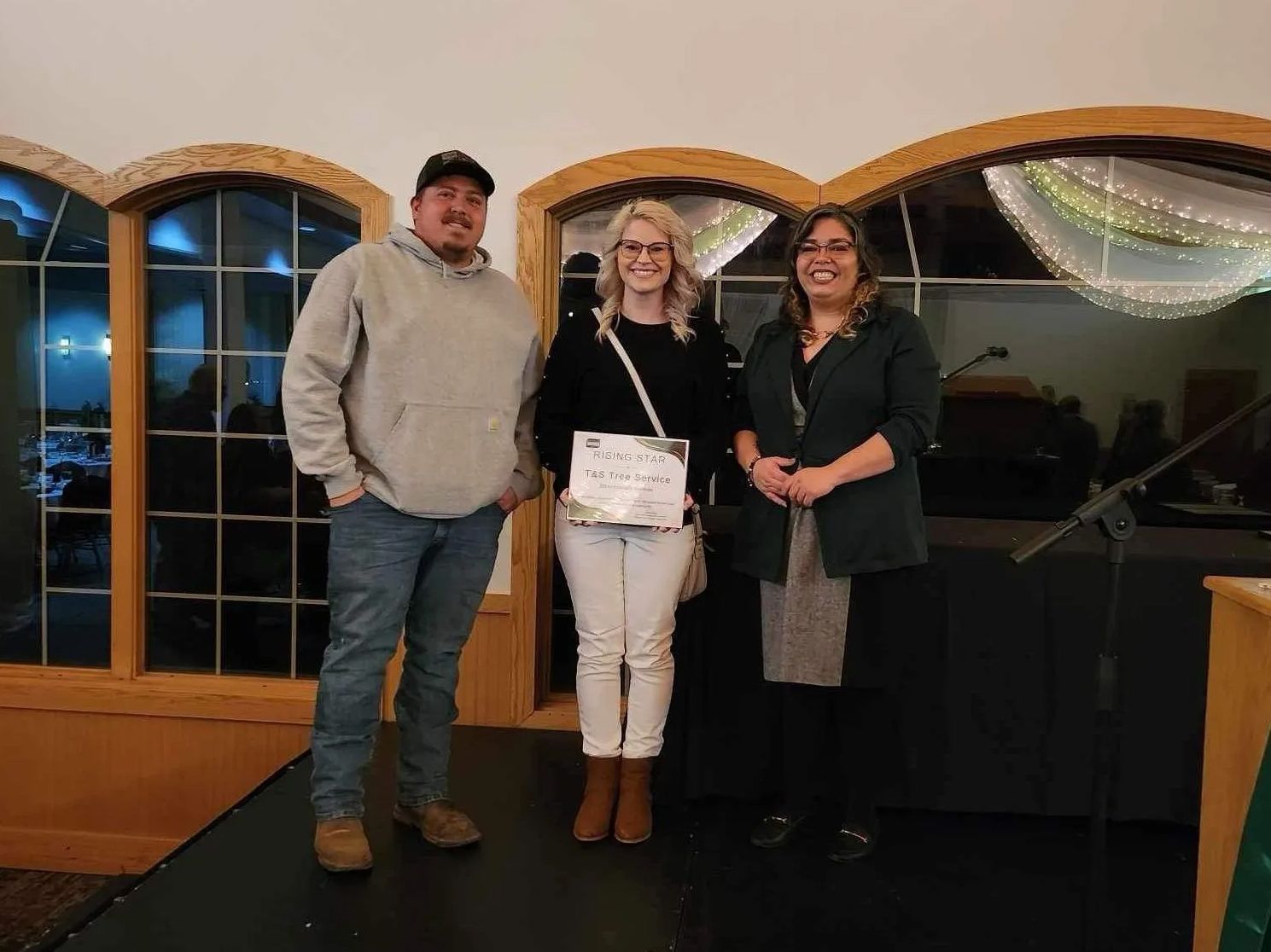 a man and two women are standing on a stage in a room .