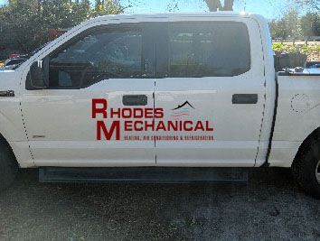 A white truck with a red logo on the side is parked in a parking lot