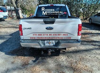 A white truck with Rhodes Mechanical written on the back window