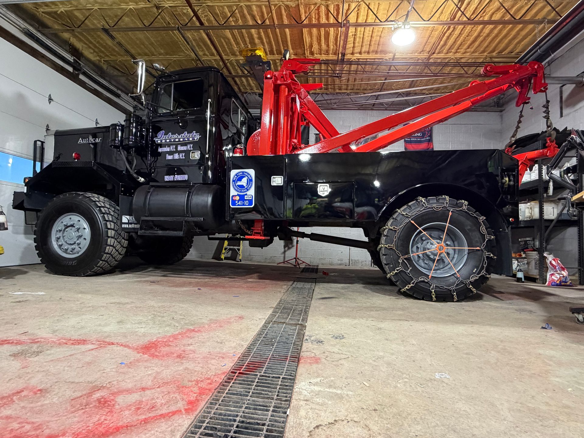 Black utility truck with red crane in a garage, viewed from the side.