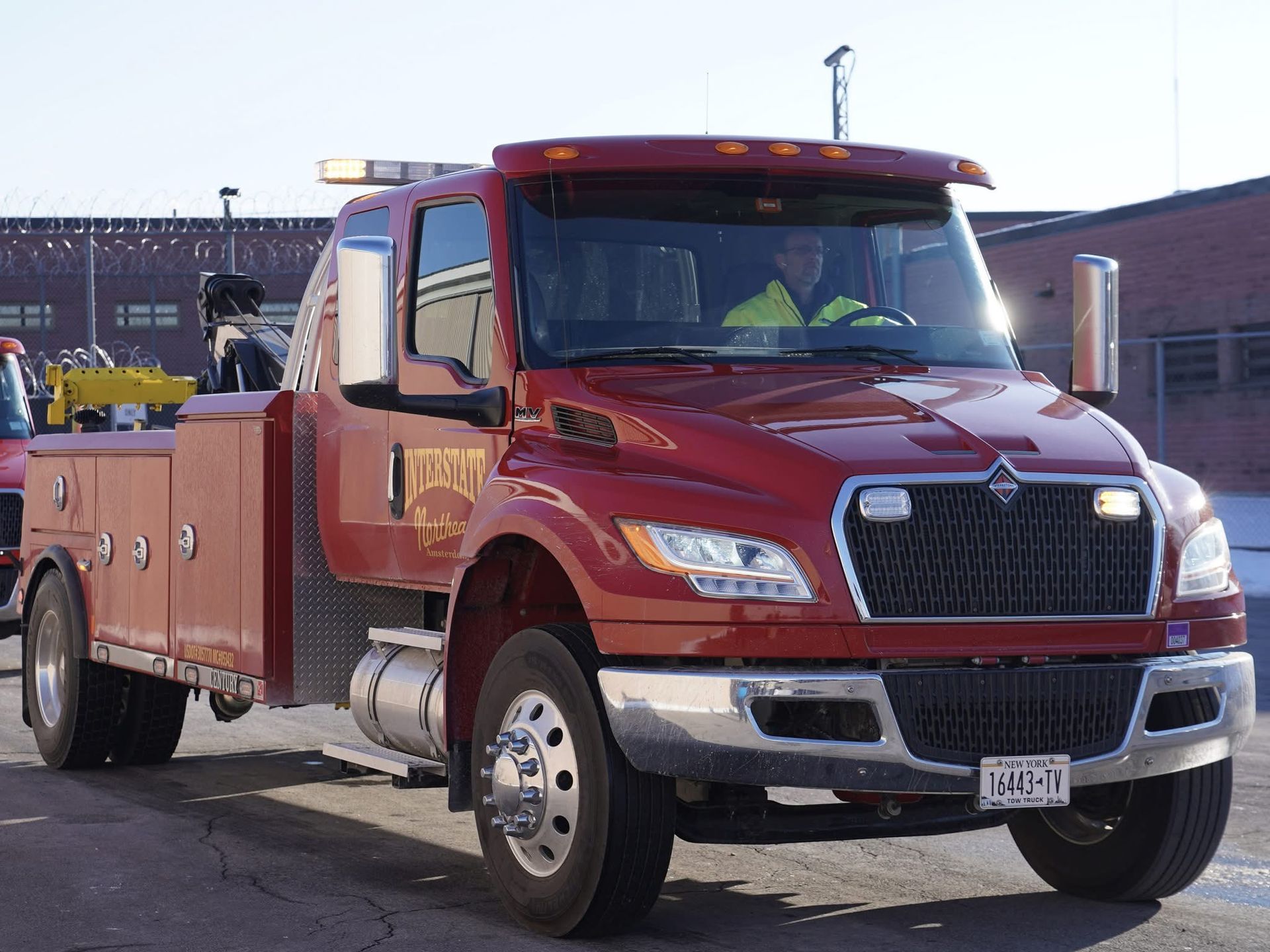Red utility tow truck parked outdoors in sunlight