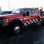 Red tow truck with black-and-white checkered stripe parked outdoors