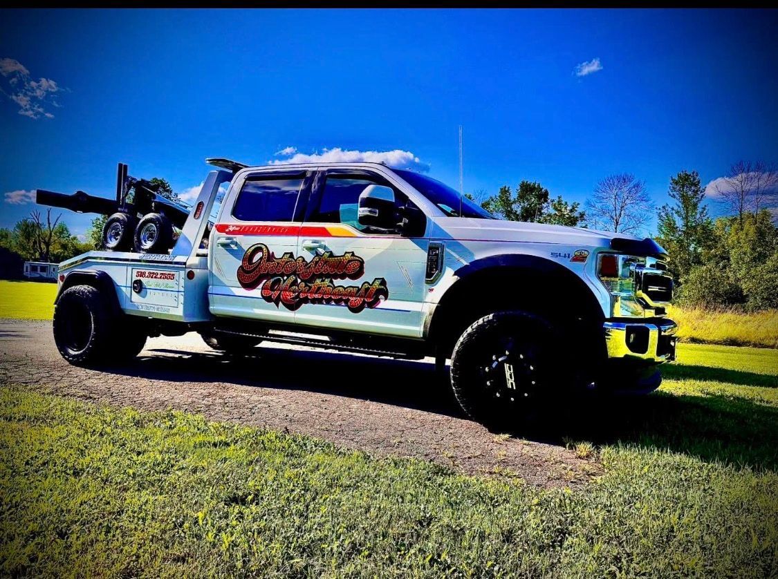 Customized white pickup truck on a grassy roadside under a bright blue sky