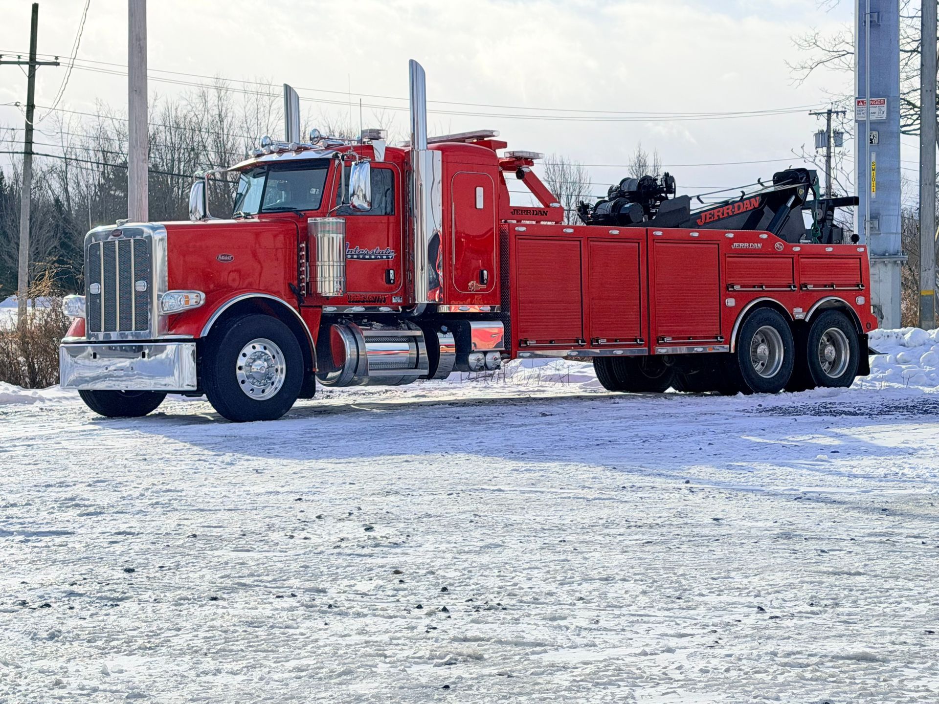 Red semi-truck with attached trailer parked on a snowy roadside