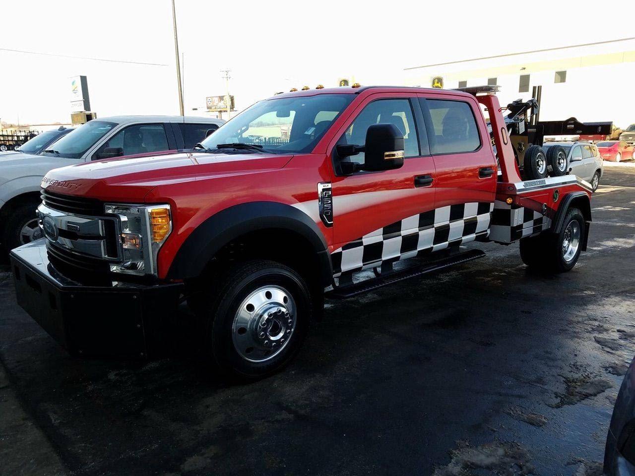 Red pickup truck with black-and-white checkered side panels parked outdoors on a lot.