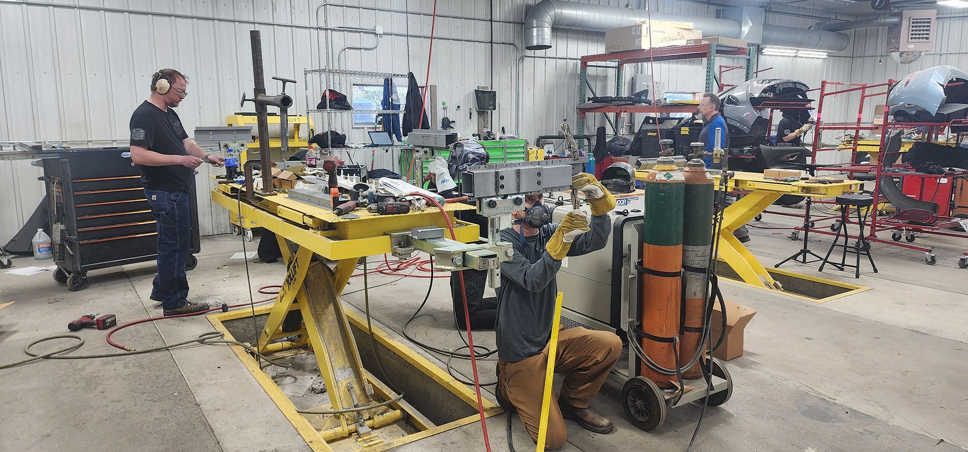 A man is kneeling down in a garage working on a machine.