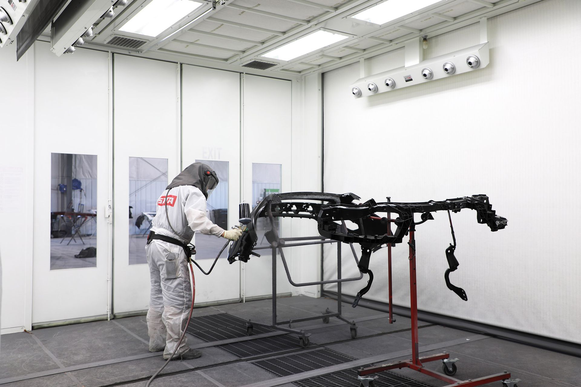 A man is painting a car in a paint booth.