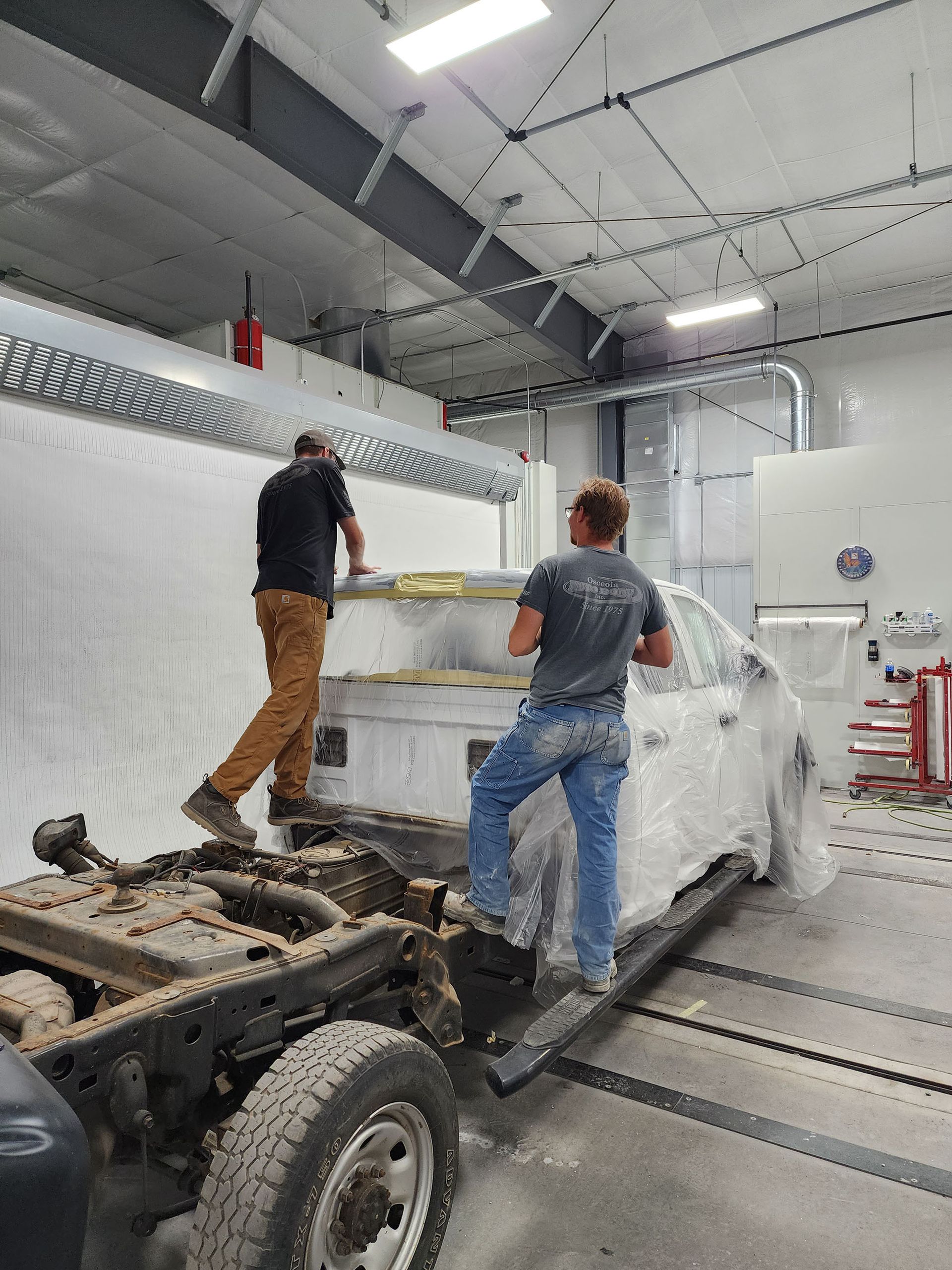 Two men are working on a car in a garage.