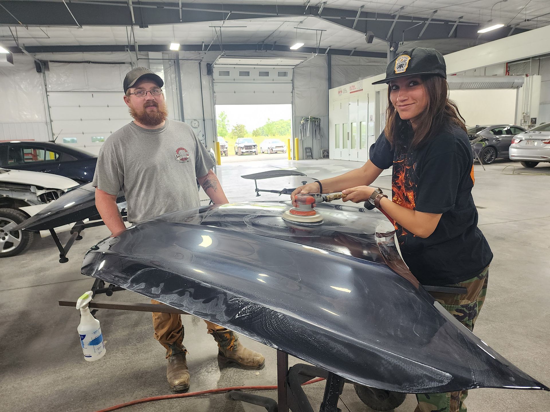 A man and a woman are working on a car in a garage.