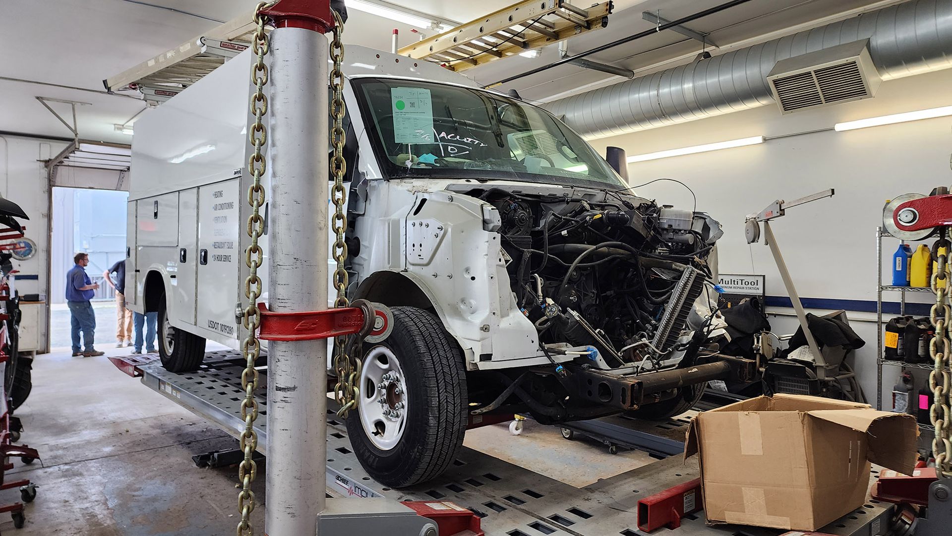 A white van is being repaired in a garage.