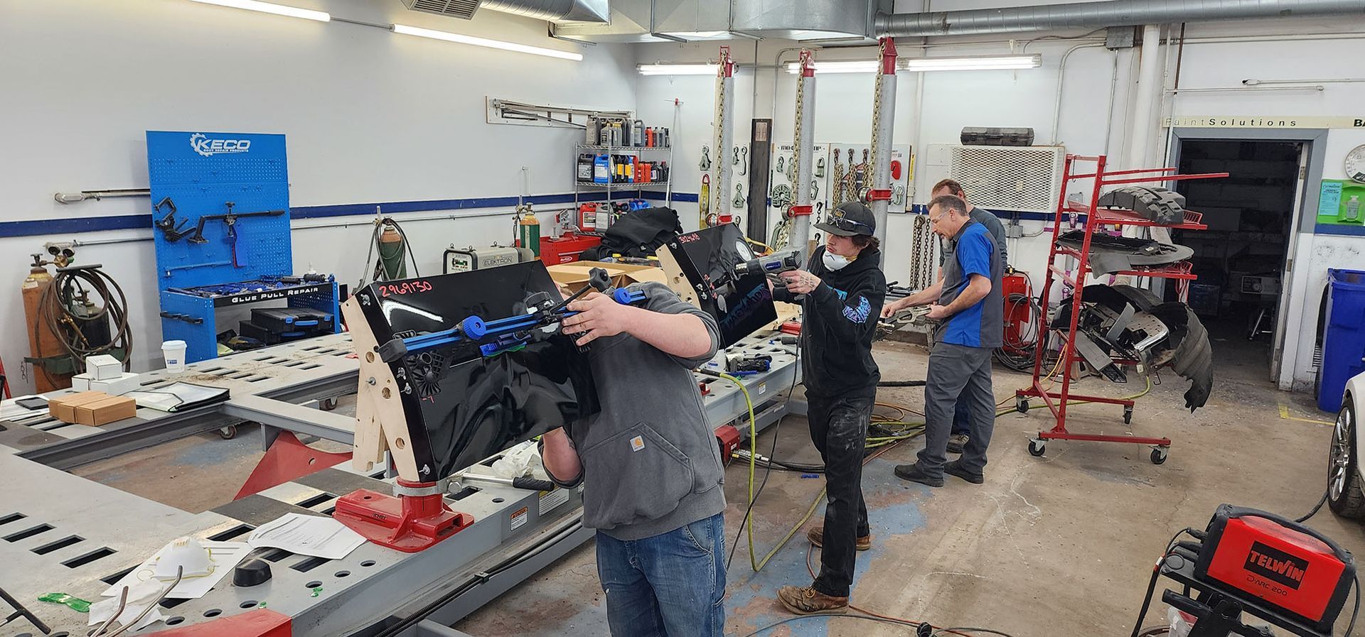 A group of people are working on a car in a garage.