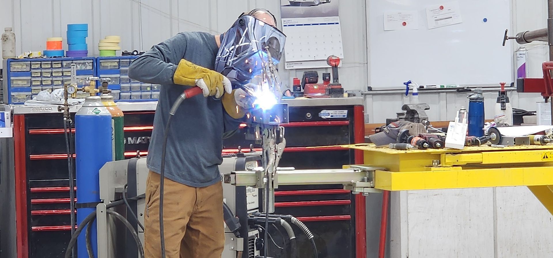 A man is welding a piece of metal in a garage.
