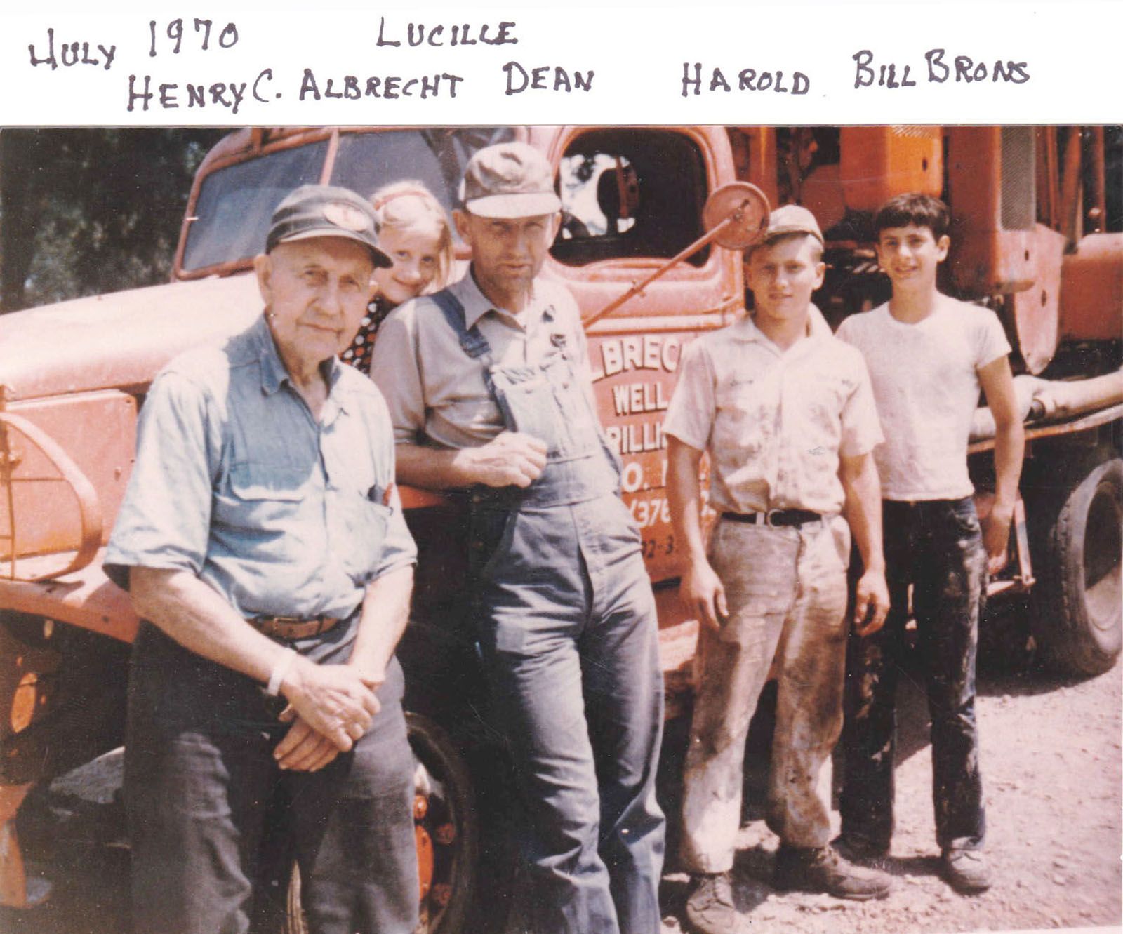 Four men stand beside a red truck