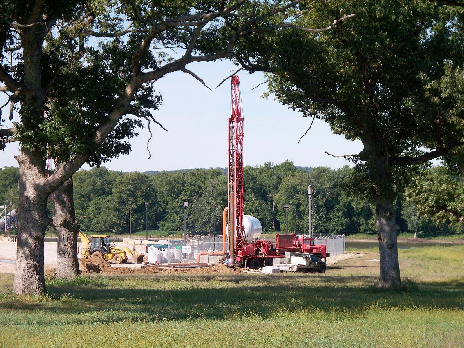 Red drilling rig and construction equipment in a grassy field