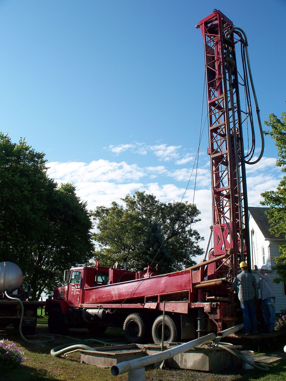 Red drilling rig on a truck at a construction site under a blue sky