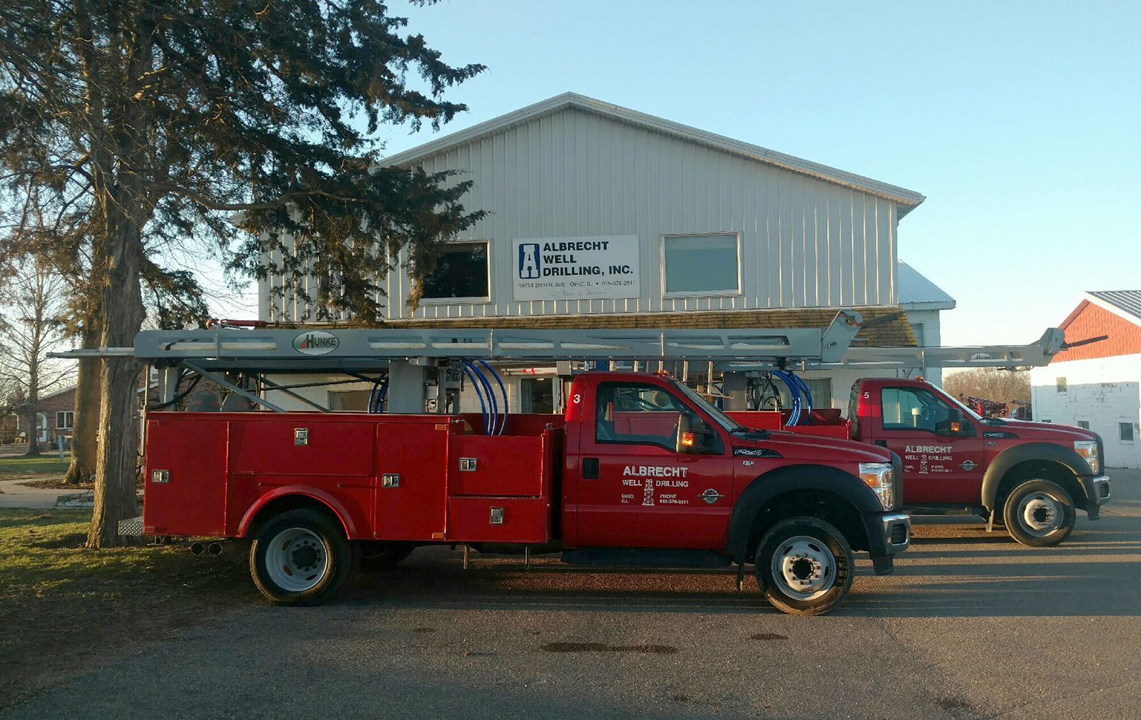 Red truck parked in front of a white building with a ladder on top