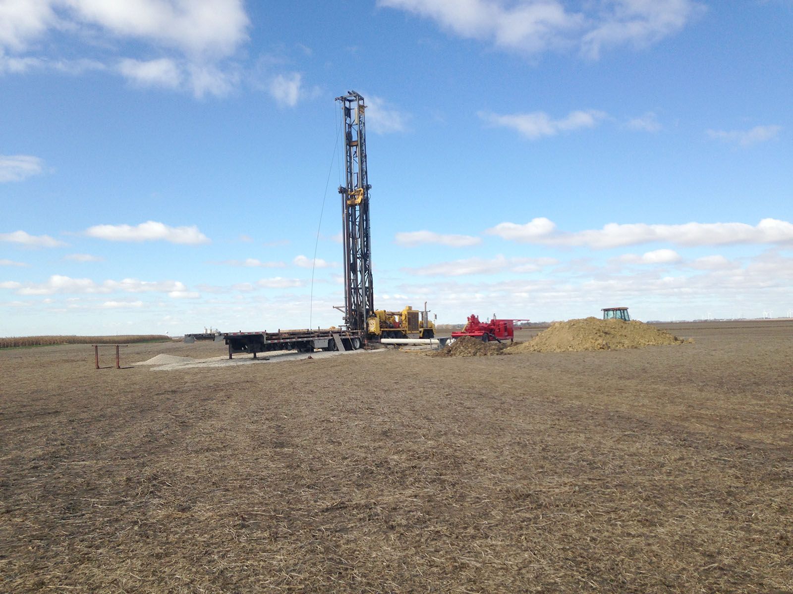 A drilling rig in a flat field under a blue sky