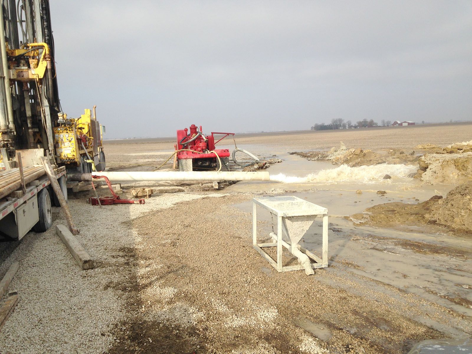 Construction equipment on a muddy work site with a red machine
