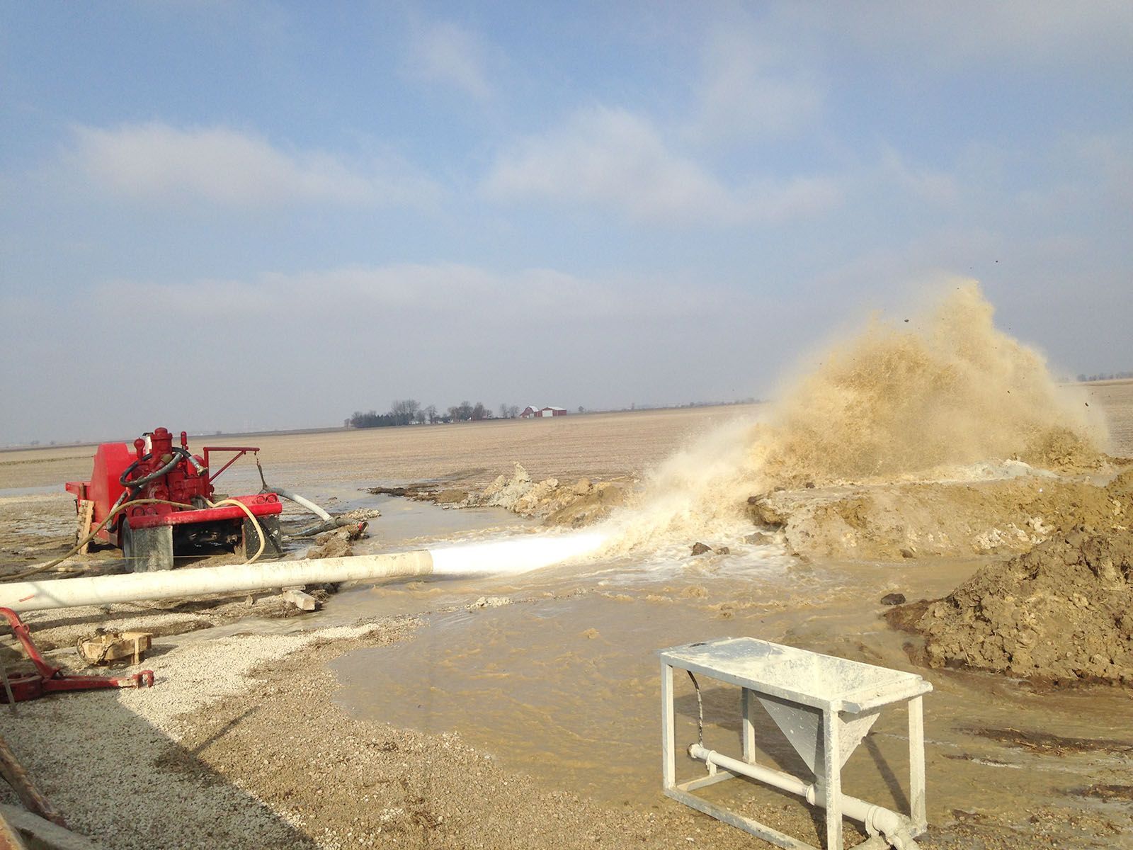 A drilling rig spraying water on a muddy field