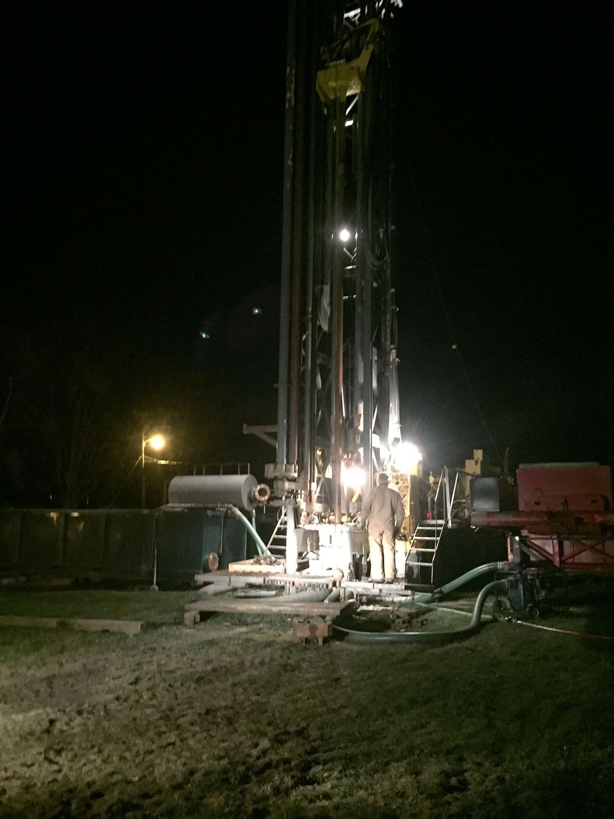 Nighttime drilling rig lit by bright work lights