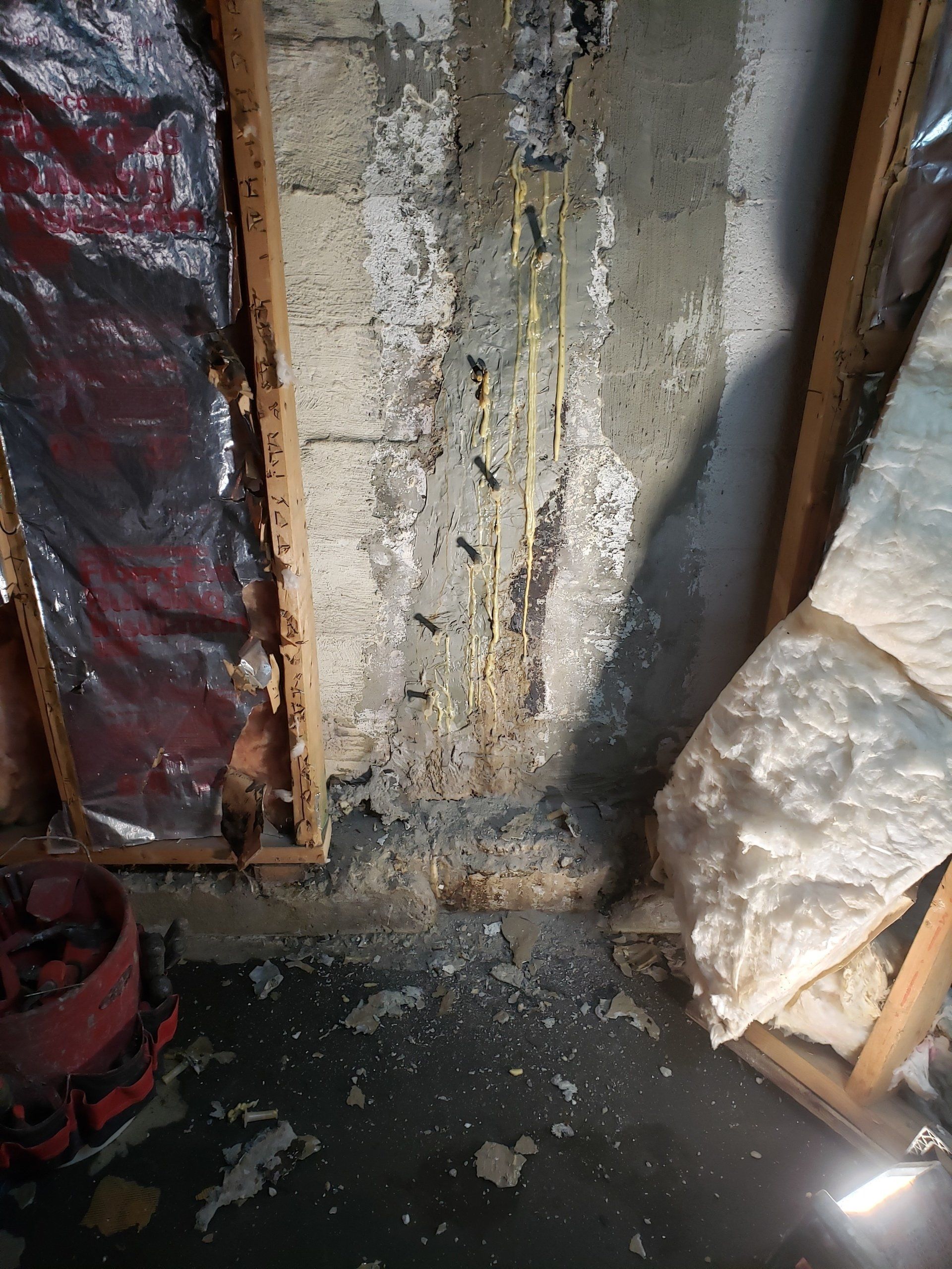 A room with a concrete wall and foam insulation on the floor.