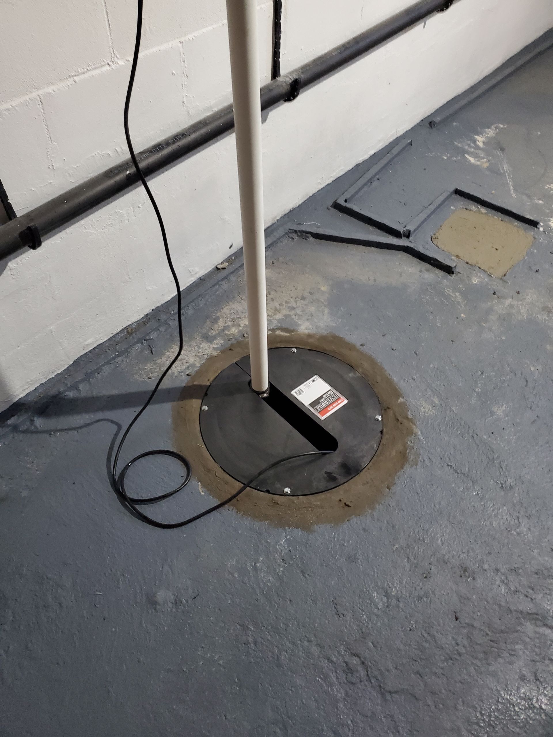 A pole is sitting on the floor in a basement next to a wall.